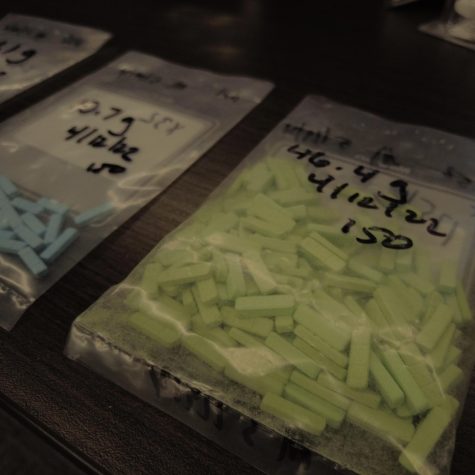 A table at the front of the presentation room held examples of counterfeit pills seized by the APD. Displayed above is a Xanax immitation pill containing fentanyl.