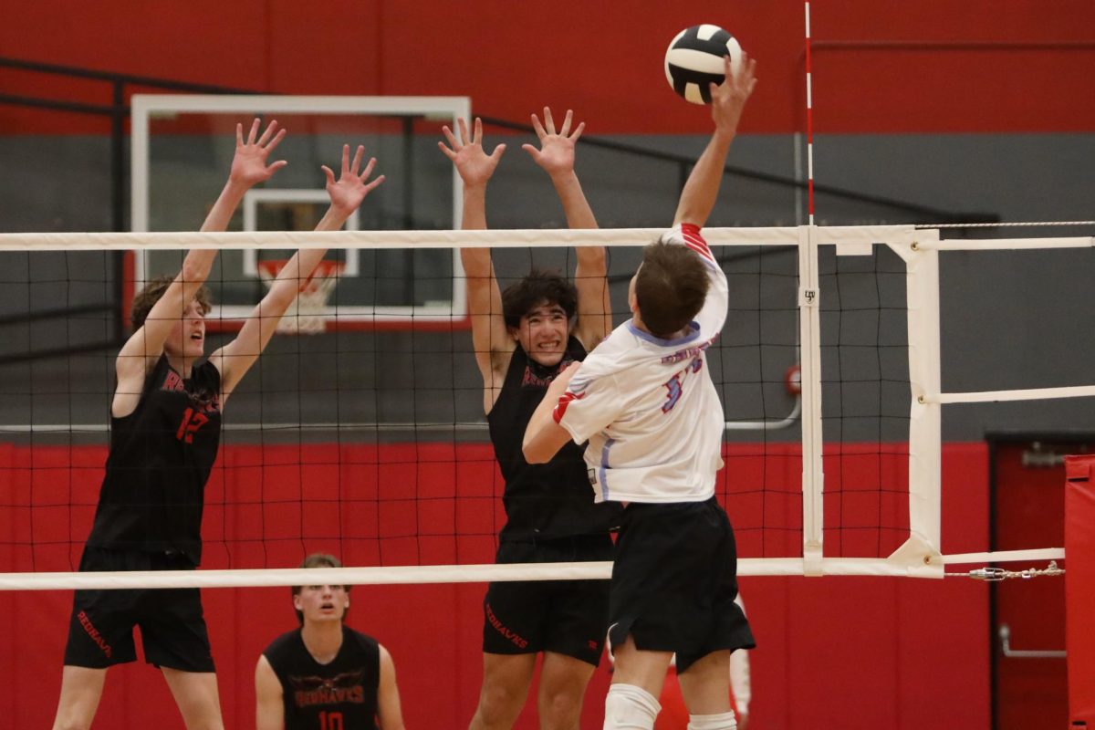 Junior Dallin Berg (left) and sophomore Derek Henriquez (right) block an attempted strike from the opposing team. Senior Jentzen Mears (bottom) stands in anticipation for the ball.