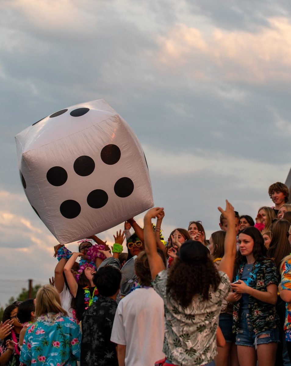 Clad in their splash zone-themed outfits, students pass an inflatable die during the football game against Bend High School on Sept. 5. Based on the number it landed on, the cheerleaders did specific activities, such as pushups and cheer offs. 