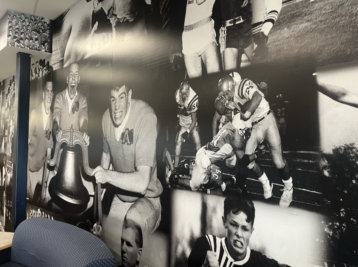 A photo of the upper level of the sports mural. There are many photos layered on both floors of the building, which span from the 1950s till the 2010s. The mural was finished after COVID, when school was back in session, in 2022.